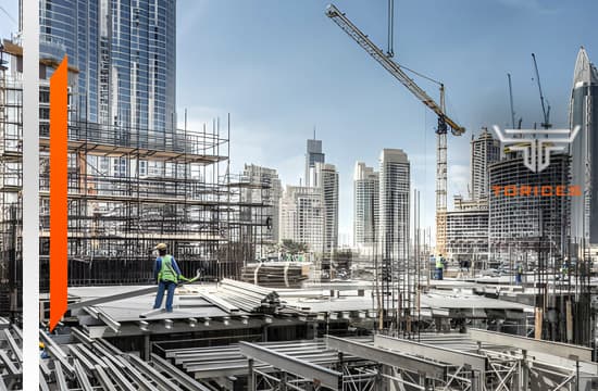 Vista panorámica de sitio de obra de edificio con estructuras y perfiles de acero, dos grúas y un trabajador de la construcción