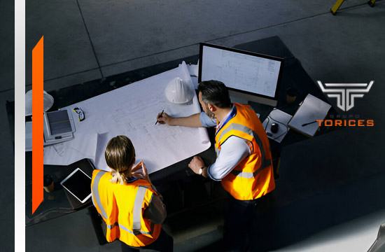 Dos ingenieros revisando un plano sobre una mesa de trabajo - Facility management